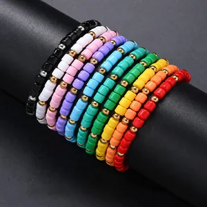 Stack of colorful clay heishi bead bracelets with gold accents on a black display.
