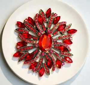 Macro view of a luxury red crystal brooch featuring an ornate rhinestone floral pattern