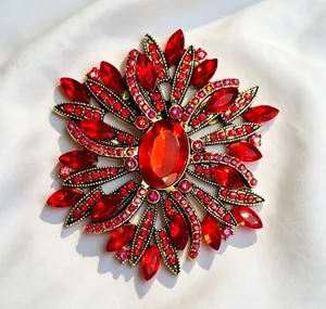 Close-up of luxury starburst brooch with vibrant red crystals and gold-tone finish