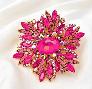 Detail shot of a large sunburst brooch with hot pink crystals on white silk background.