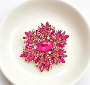 Close-up of fuchsia crystal floral brooch with iridescent rhinestones in antique gold setting