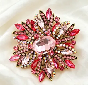 Elegant luxury flower brooch featuring pink and red crystals on white silk background