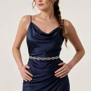 Detail van een luxe kristallen tailleketting met strass op een blauwe satijnen jurk.