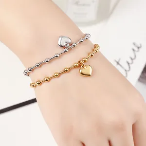 Close-up view of stainless steel beaded bracelets with heart charms on a wrist.