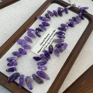 Close-up of irregular natural amethyst chip necklace on wooden display tray