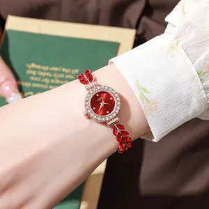 Close-up of elegant ladies' rose gold leaf-shaped watch with red gemstones on wrist.