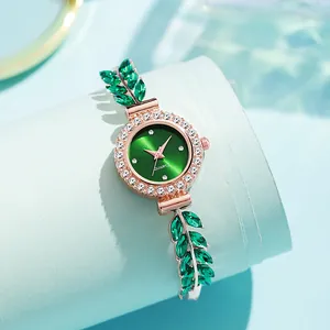 Detailed view of women's rose gold watch with emerald leaf bracelet and rhinestone bezel