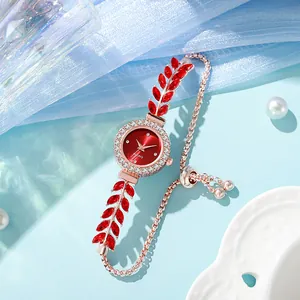 Close-up of rose gold leaf bracelet watch with red dial and rhinestone details