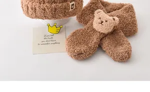 Gros plan d'un ensemble hiver enfant marron duveteux avec bonnet, écharpe et petit ours en peluche