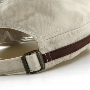 Detailansicht der verstellbaren Metallschnalle und des Lederbesatzes an der beigen Militärkappe