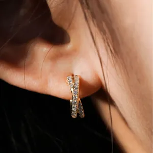Detailansicht eleganter goldfarbener Cross-over-Creolen mit funkelnden Zirkoniasteinen