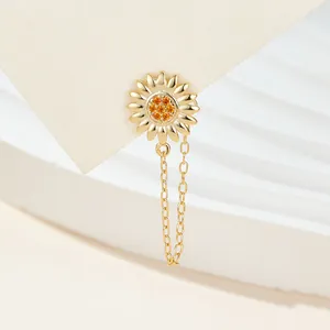 Close-up of golden sunflower stud earring with orange stones and delicate tassel chain