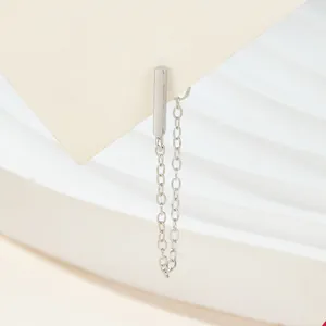 Detail showing a minimalist silver bar stud earring with a delicate long chain tassel