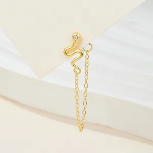 Close-up of a gold-plated snake-shaped stud earring with a hanging tassel chain detail