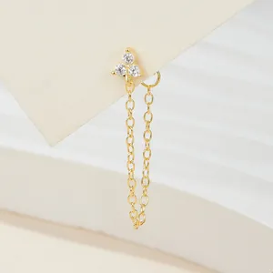 Detailed view of a gold chain tassel earring with three sparkling clear zircons