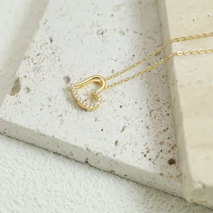 Close-up of gold heart-shaped pendant necklace with sparkling diamonds on a textured stone