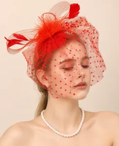Detalle de un elegante tocado de novia rojo con plumas y velo de red con lunares