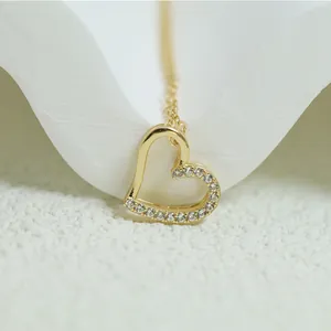 Detail shot of an elegant gold heart pendant necklace featuring sparkling inset crystals