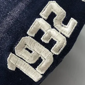 Macro-opname van het hoogwaardige witte 1932 borduurdetail op de blauwe katoenen baseballpet.