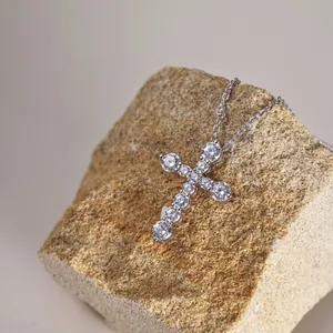 Vue détaillée d'un collier croix en argent S925 avec zircons scintillants sur une pierre.