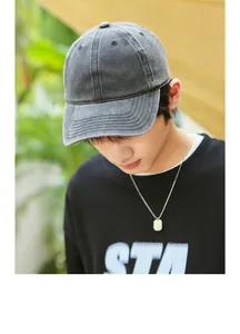 Close-up of a washed distressed dark grey cotton baseball cap worn by a model