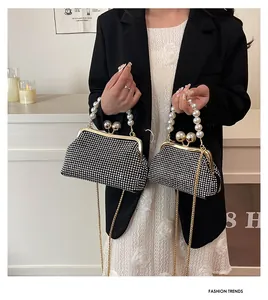 Close-up detail of black rhinestone evening clutch with pearl handle and gold chain strap