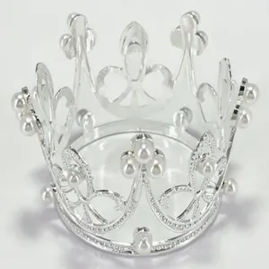 Macro detail of a silver alloy mini crown with white pearl accents for cake or hair decor