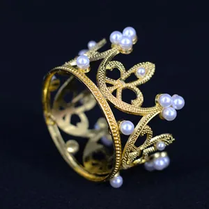 Detailed macro shot of a mini golden alloy crown with white pearl decorations.