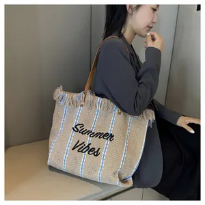 Grande borsa da spiaggia tessuta con ricamo 'Summer Vibes' tenuta da una modella