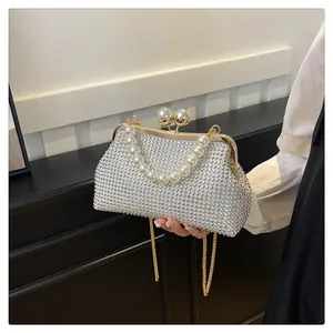 Detail view of elegant pearl handle shell clutch bag with shimmering rhinestone exterior.
