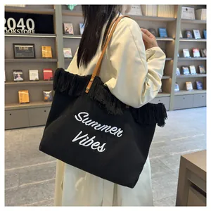 Dettaglio della borsa tote in tela nera con ricamo Summer Vibes e frange decorative