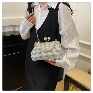 Elegant silver rhinestone evening clutch bag with pearl handle shown on a stylish model.