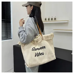 Dettaglio di una grande borsa tote in tela con ricamo Summer Vibes e bordo frange