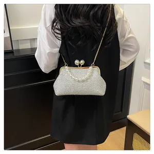 Detailed view of the white beaded shell evening bag with pearl handle worn by a model