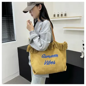 Dettaglio della borsa tote in tela gialla con ricamo 'Summer Vibes' e frange