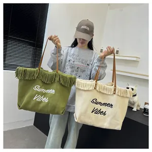 Grandi borse tote in tela con frange e ricamo Summer Vibes mostrate da una modella