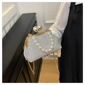 Close-up of elegant rhinestone evening clutch with large pearl handle and gold chain