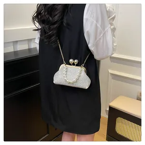 Elegant white evening shell bag with sparkling rhinestone and pearl details on a model