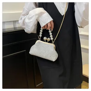Detailed view of an elegant silver rhinestone shell clutch bag with a luxury pearl handle