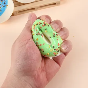 Realistic green PU simulation donut fridge magnet being squeezed in hand for stress relief.