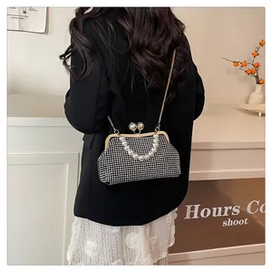 Elegant pearl handle shell bag with rhinestone texture being worn as a crossbody purse