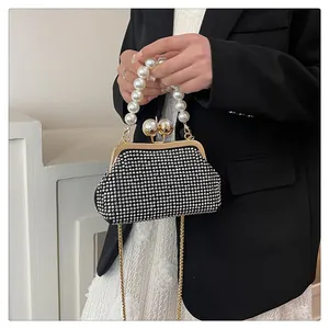 Elegant black shell-shaped clutch bag with large pearl handle and rhinestone embellishments
