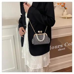 Elegant black pearl-handled evening bag with rhinestone detailing worn over a chic blazer.