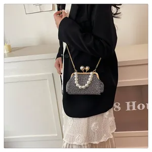 Model wearing a black pearl shell bag with gold chain strap and elegant pearl handle