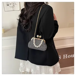 Model wearing elegant pearl handle shell bag with rhinestone detail and gold chain strap