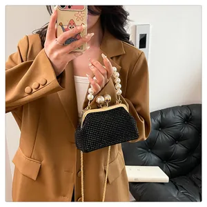 Elegant black pleated clutch bag with pearl handle and gold chain details.