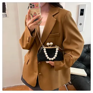 Fashionable black rhinestone clutch with pearl handle worn with a brown blazer jacket.