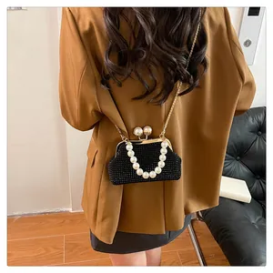 Close-up of a black rhinestone shell bag with elegant pearl handle and gold chain