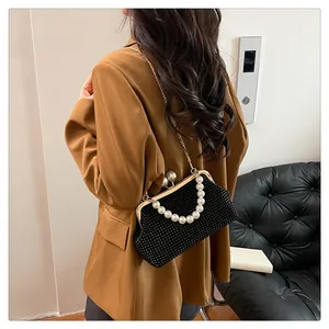 Black textured clutch bag with pearl handle worn with a brown blazer