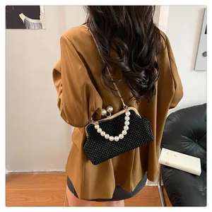 Elegant black pleated shell bag featuring a pearl handle, shown being worn by a fashion model.